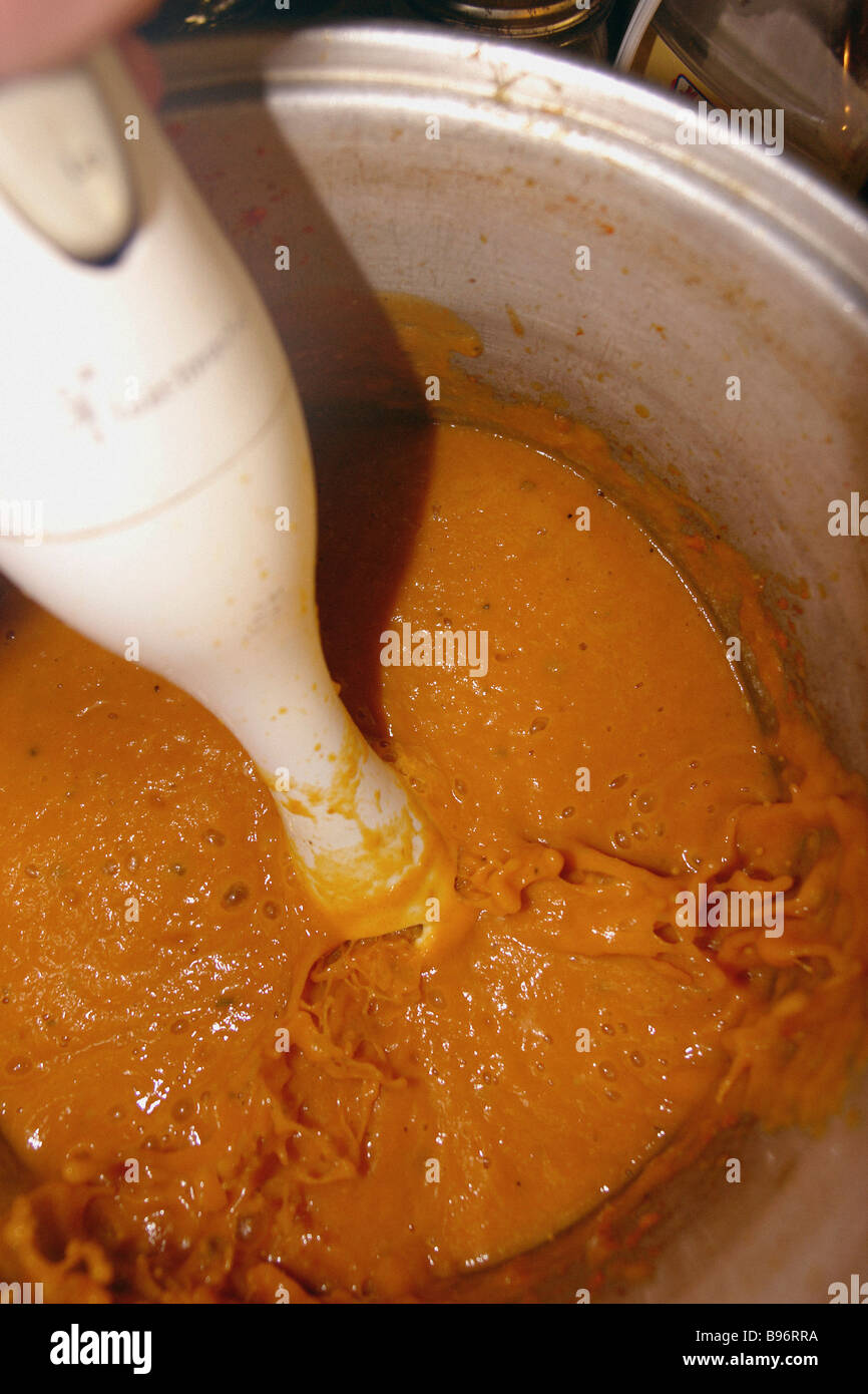 Still Life of Carrot and Pumpkin Soup Being Pureed by Immersion Blender Seen from Above Copy Space Stock Photo