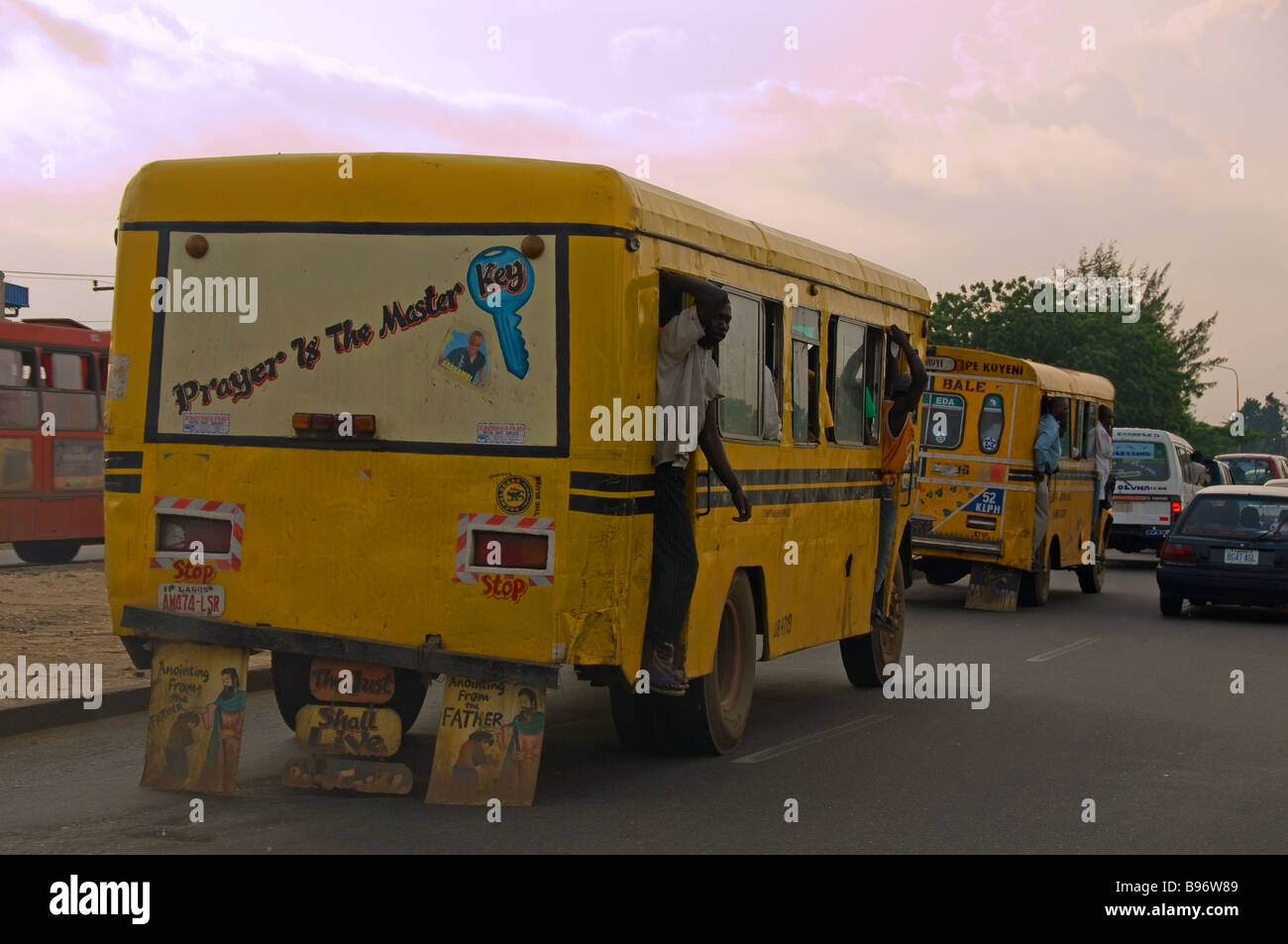 Man hanging out of the rear door of a crowded public bus in Lagos, Nigeria Stock Photo