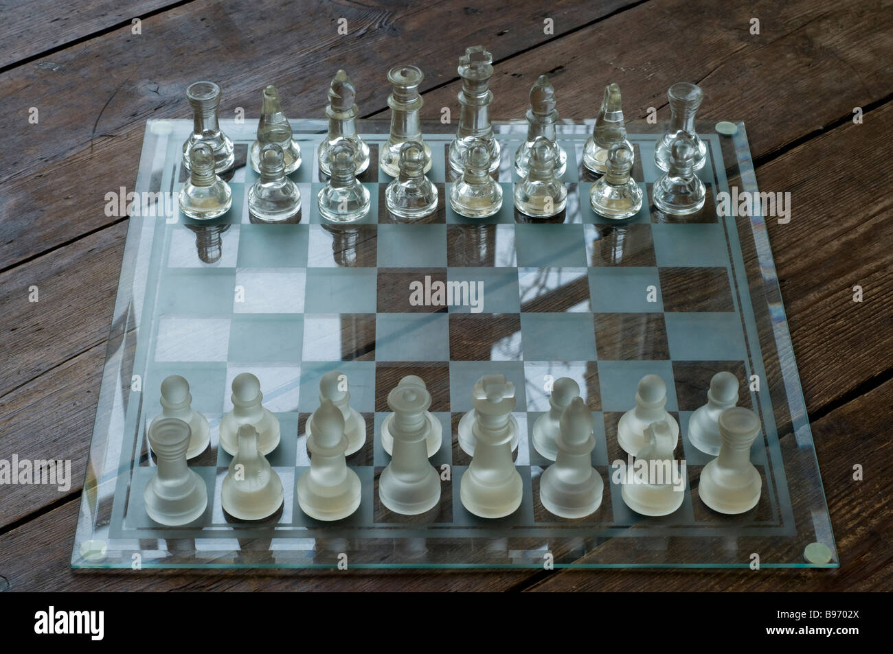 Glass chess set on a wooden floor Stock Photo
