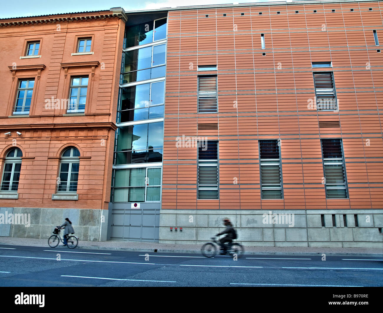 Bicycle and motorcycle passing in front of a modern building in Toulouse France Stock Photo