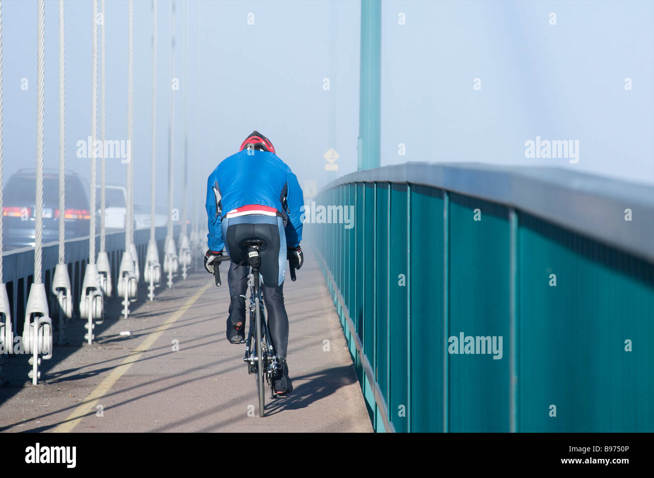 Man riding bike across Lions Gate Bridge in the fog, Vancouver, British ...