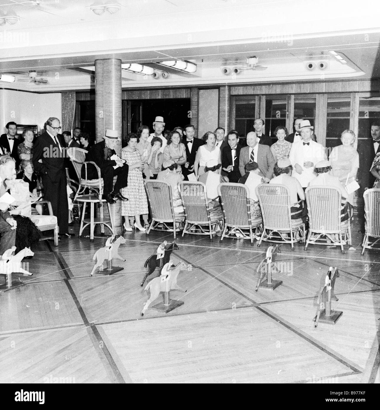 1950s, historical, evening & cruise passengers on a steamship of the British India Steam Navigation Co having fun playing a horse racing game inside. Stock Photo