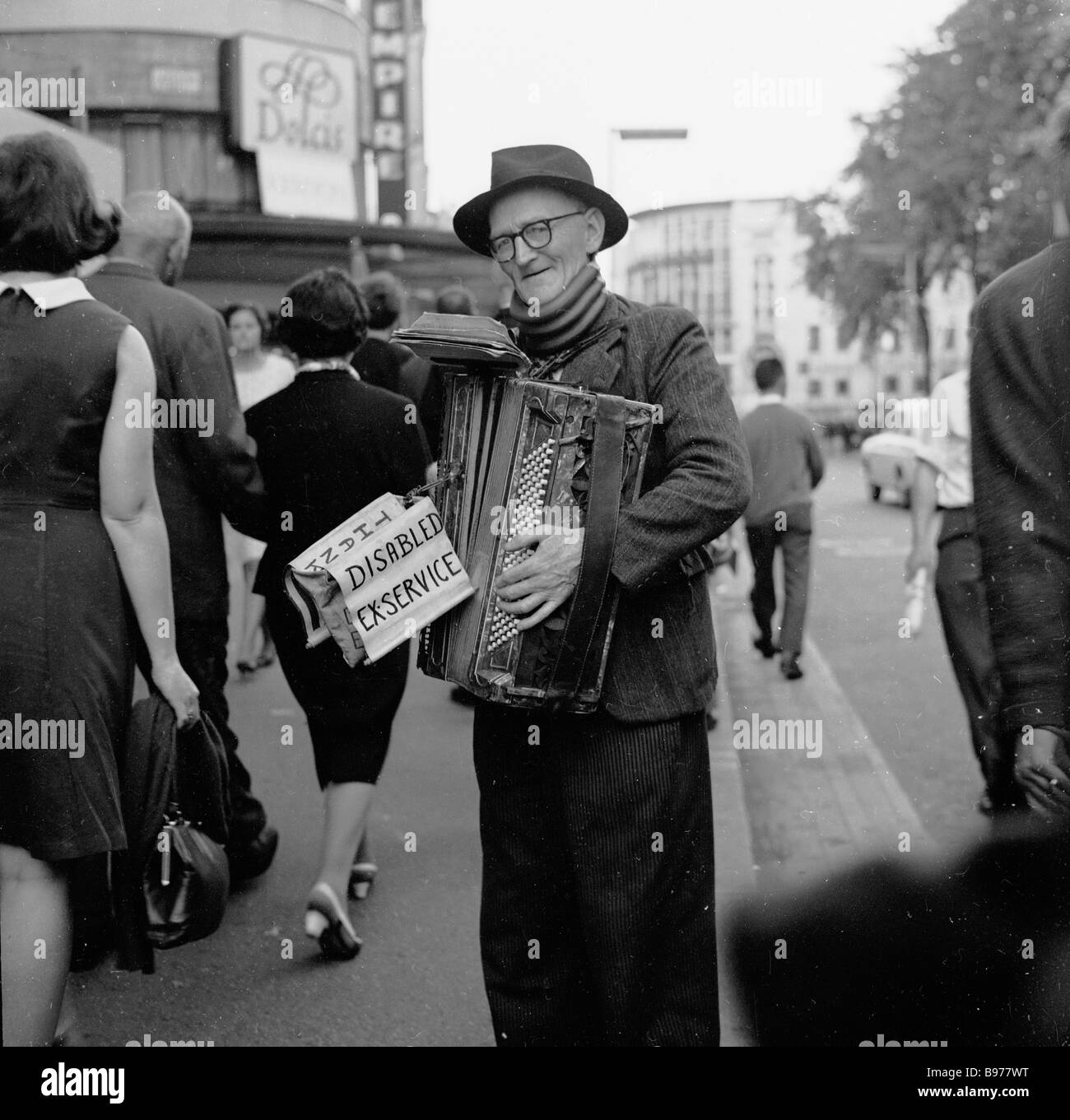 Elderly street busker, 1950s. A disabled ex-serviceman or soldier playing a squeeze box in the street at Leicester Square, London, England, UK. Stock Photo