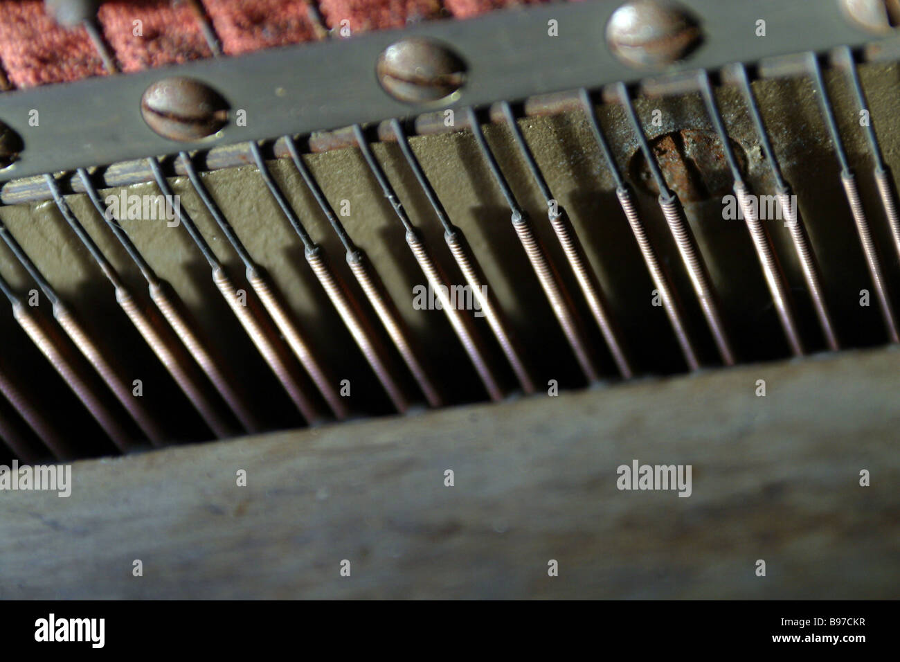 Inside workings of a piano showing steel strings dampers and tuning nuts and wooden frame Stock Photo