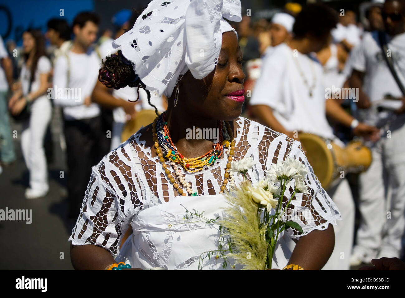 A black bahian woman in traditional dress holding flowers at the Lavagem do Madeleine celebration in Paris, France. Stock Photo