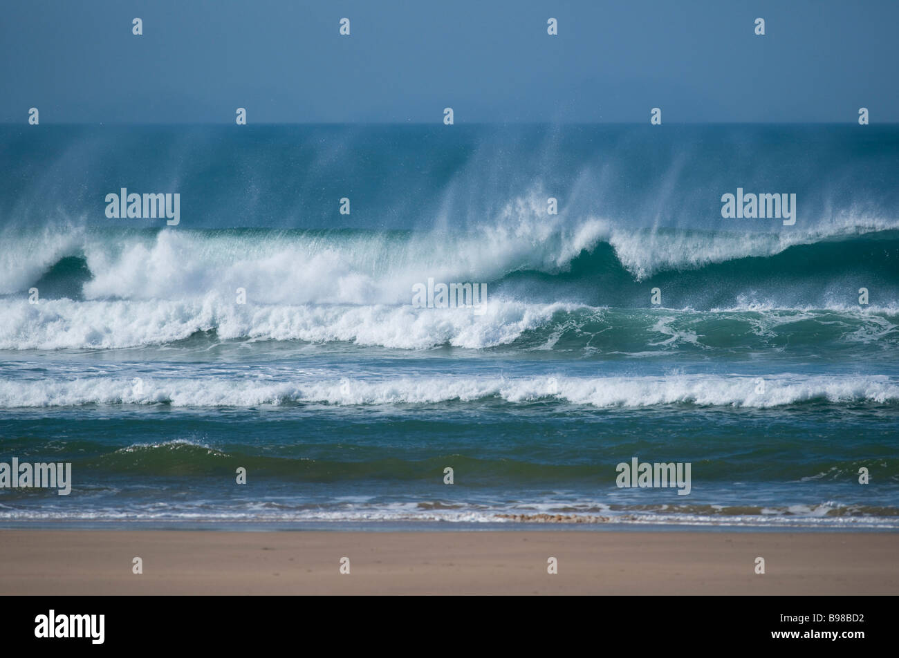 Waves crashing on the shore with spray and sand Stock Photo