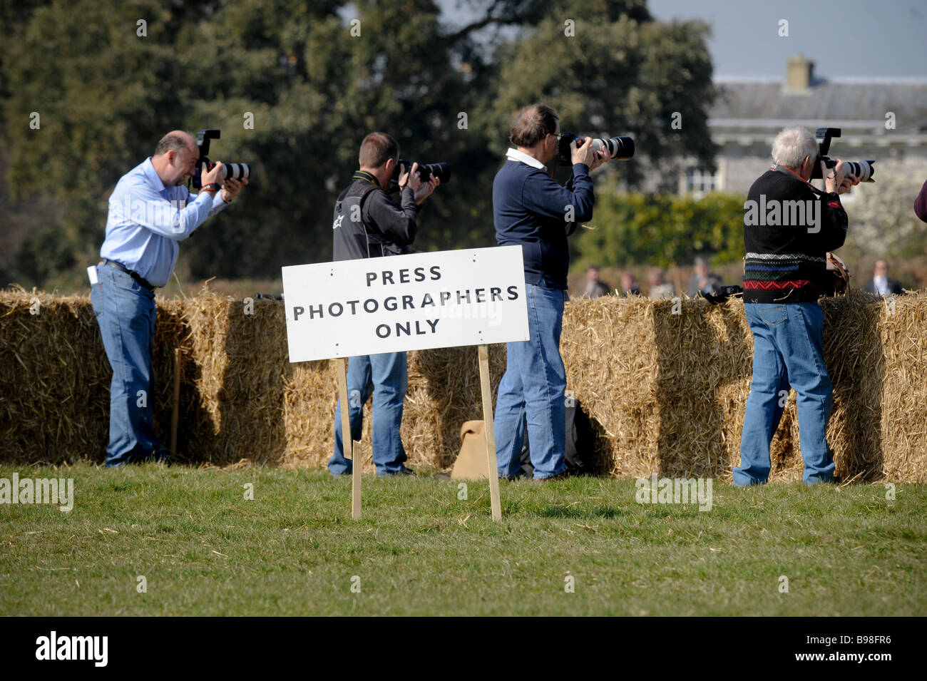 Press photographers in a reserved area marked by a sign "press