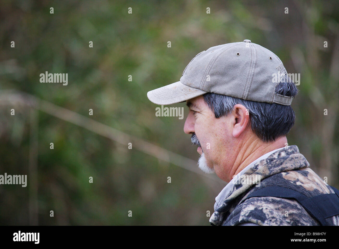 SIDE VIEW CLOSEUP HUNTING GUIDE BROWNING HAT BROWNING VEST GRAYING HAIR Stock Photo