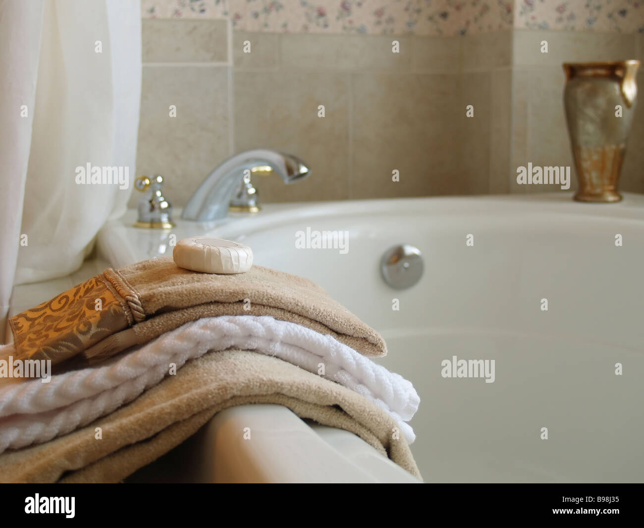 Towels and a bar of soap on the side of a large bathtub Stock Photo Alamy