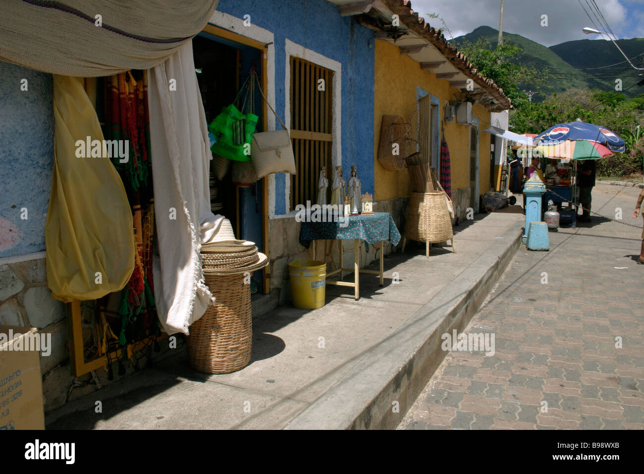 Street in town. Rows of terraced houses.  Shops. Doorways. Goods on display. EL VALLE. ISLA MARGARITA. VENEZUELA. Stock Photo