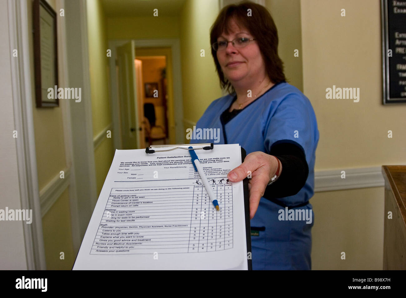 Woman, receptionist at doctor's office handing patient form on clipboard Stock Photo