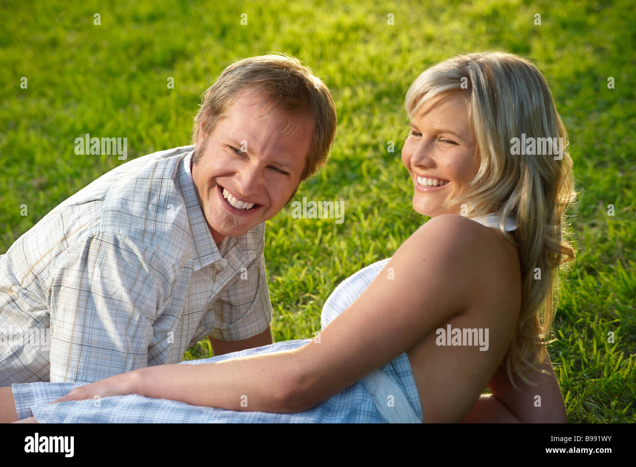 Couple lying on grass in park Stock Photo