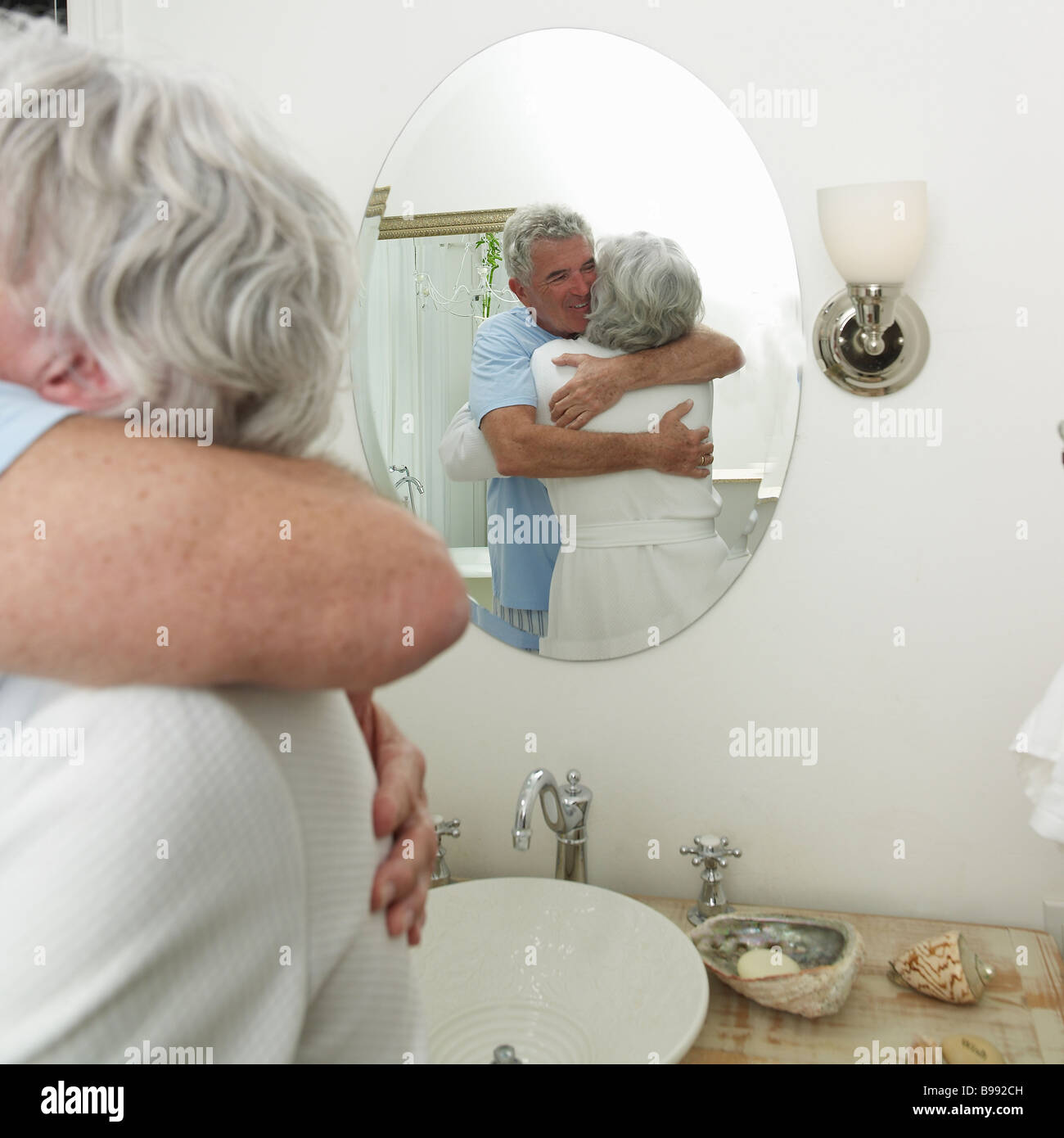 Women hugging man in bathroom reflection in mirror Stock Photo