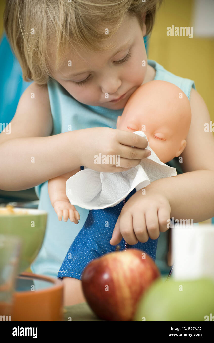 Little girl wiping baby doll's face with paper towel Stock Photo Alamy