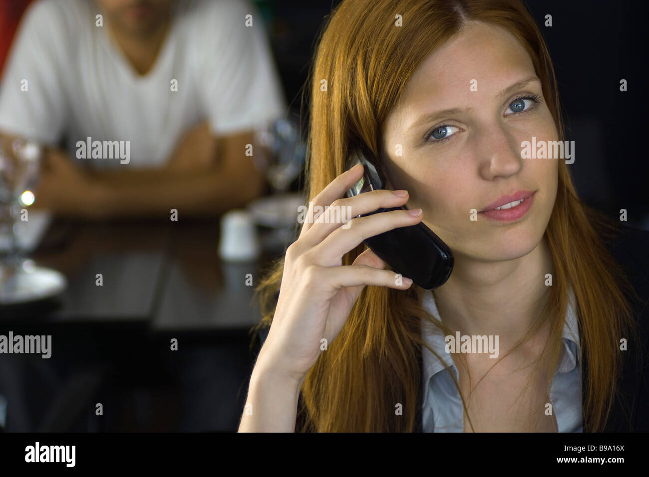 Woman holding cell phone to ear, smiling at camera Stock Photo