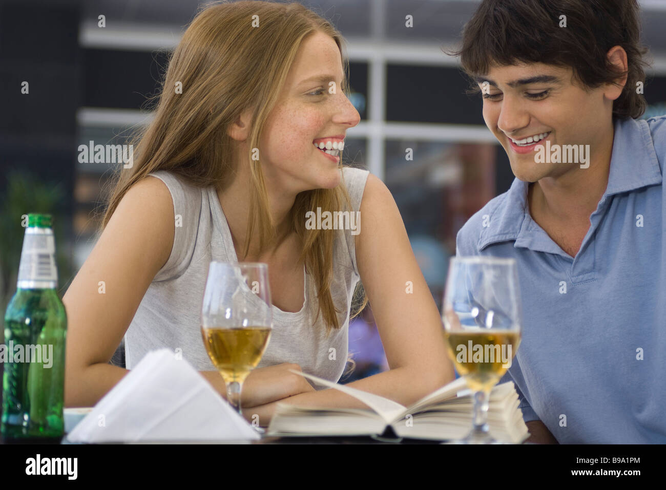 Young couple sitting at outdoor cafe, looking at book together Stock Photo