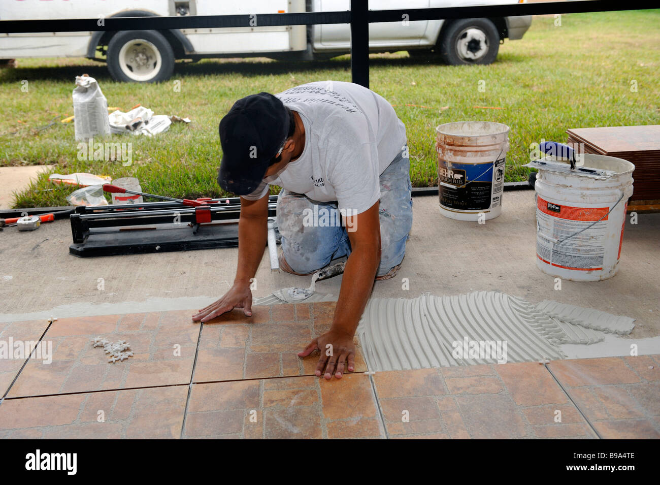 Male Hispanic Lays Ceramic Tile on Cement Floor in Patio Lanai Stock