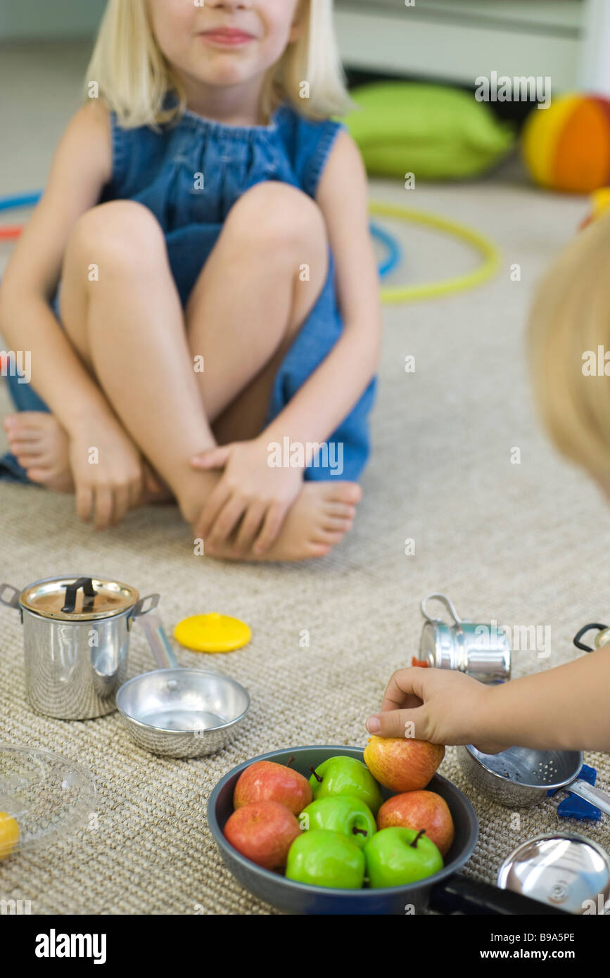Children sitting on floor, playing with pots and pans, cropped Stock