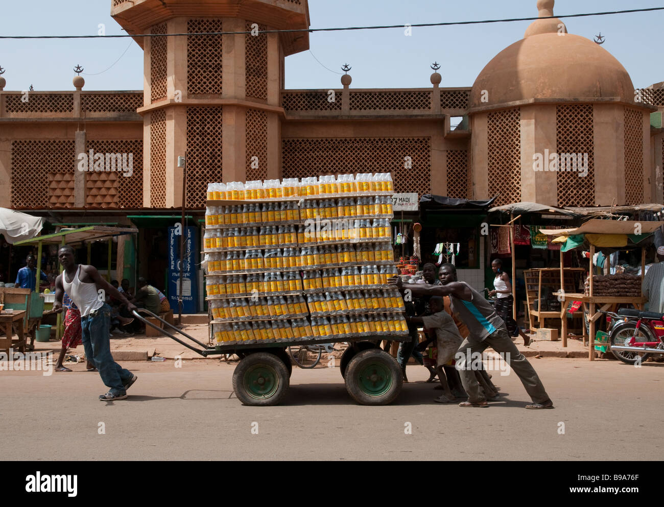 West Africa Burkina Fasso Ougadougou 3 porters pulling a heavy cart loaded with bottles Stock Photo