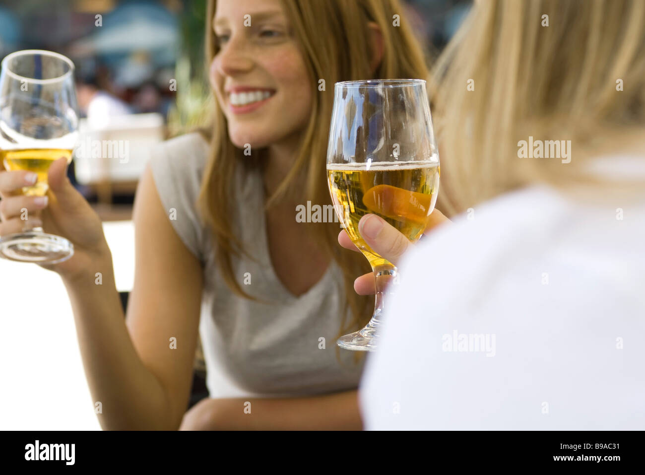 Young women drinking beer at sidewalk cafe, cropped Stock Photo