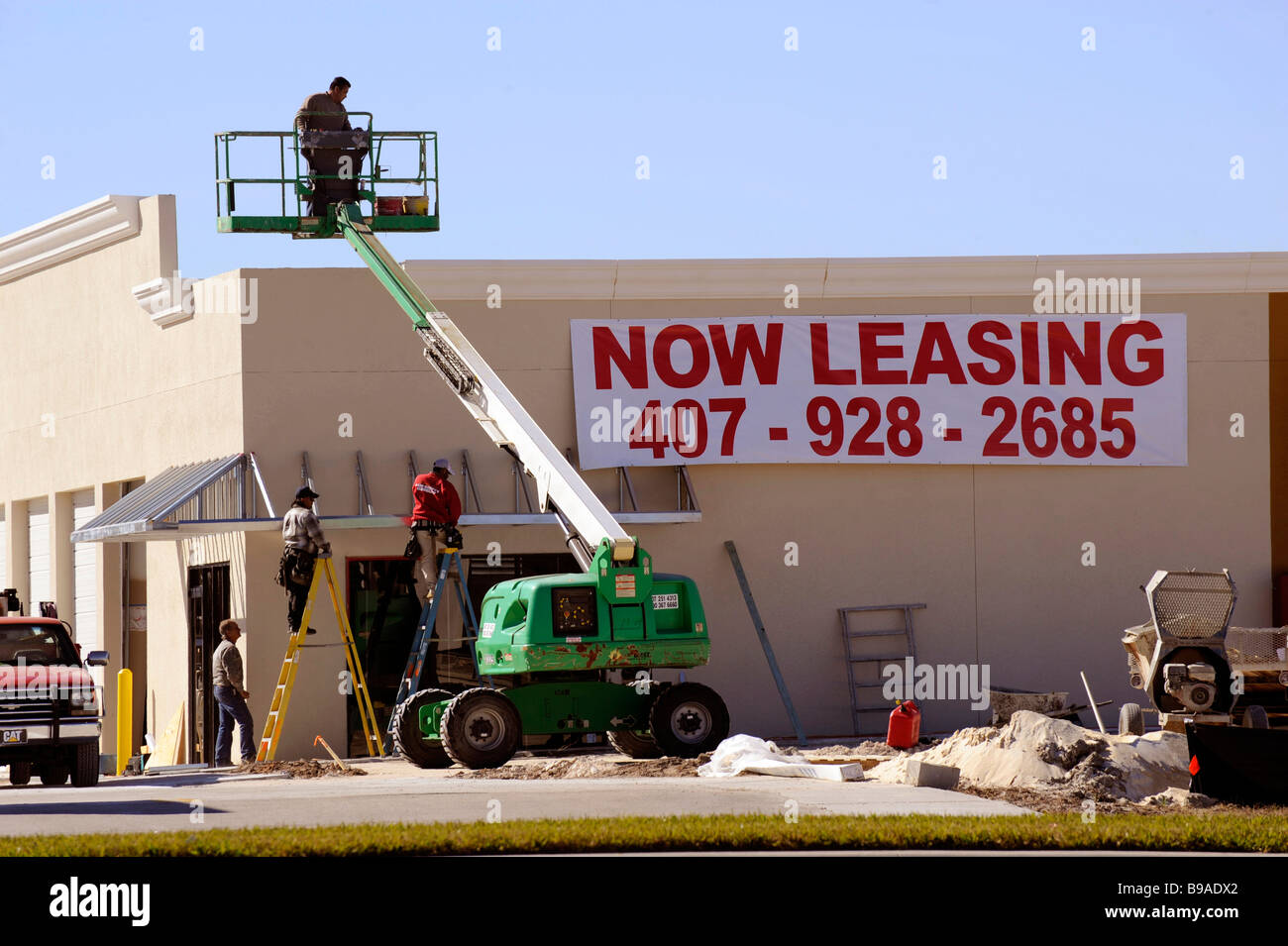 cherry picker boom lift at building construction site with now leasing sign Stock Photo