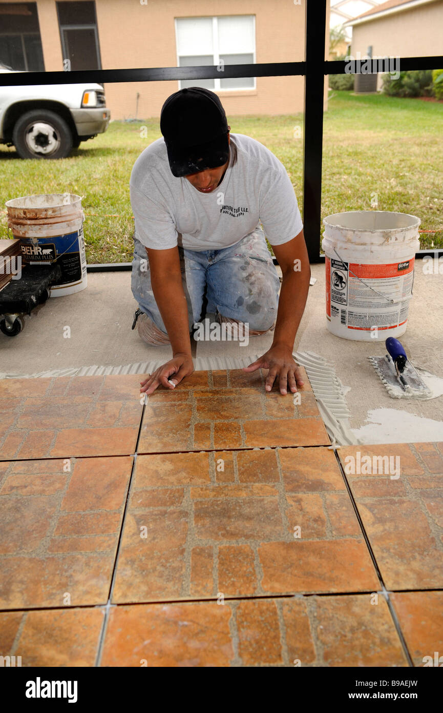 Male Hispanic Lays Ceramic Tile on Cement Floor in Patio Lanai Stock