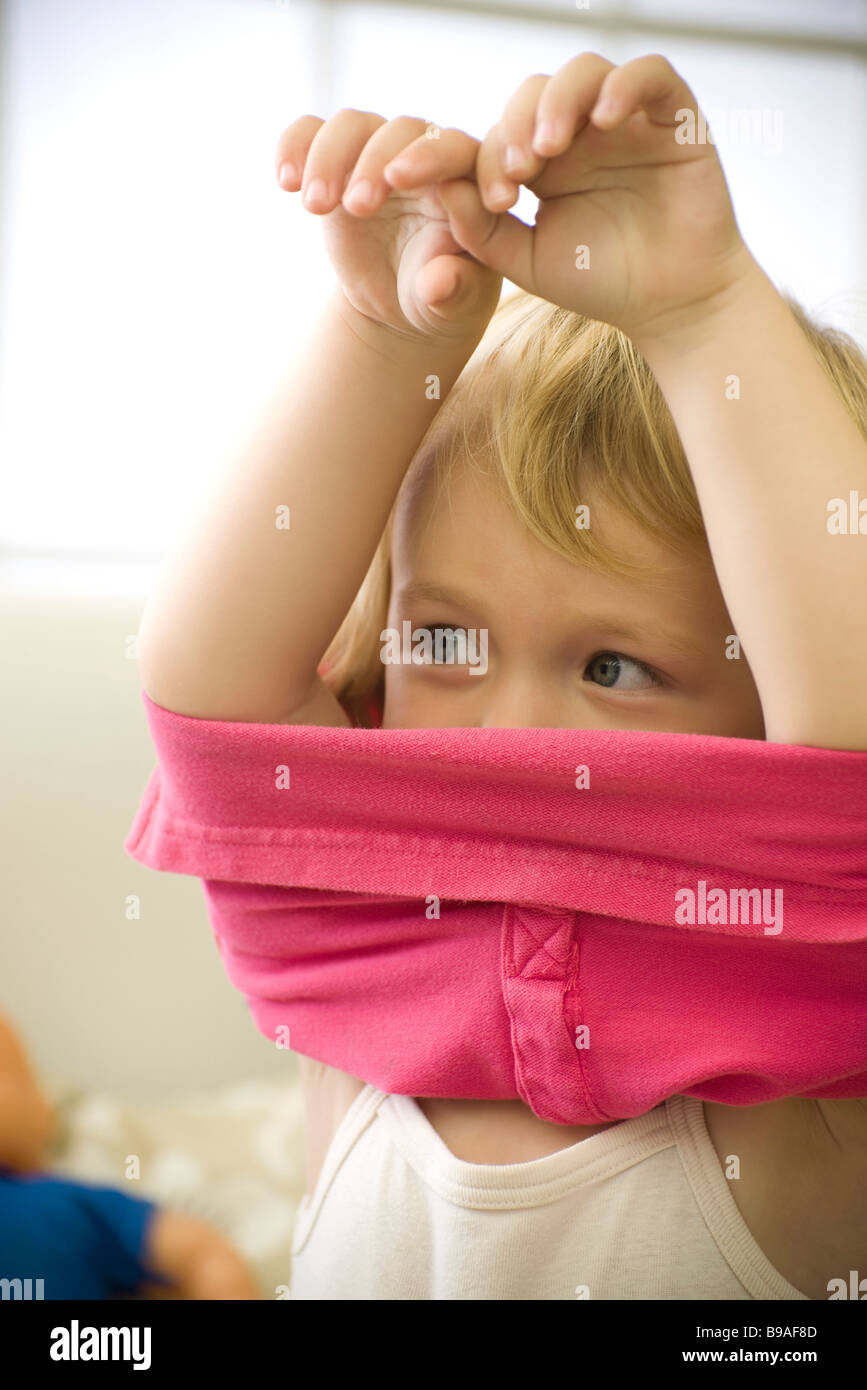 Little girl putting on shirt, arms raised Stock Photo Alamy