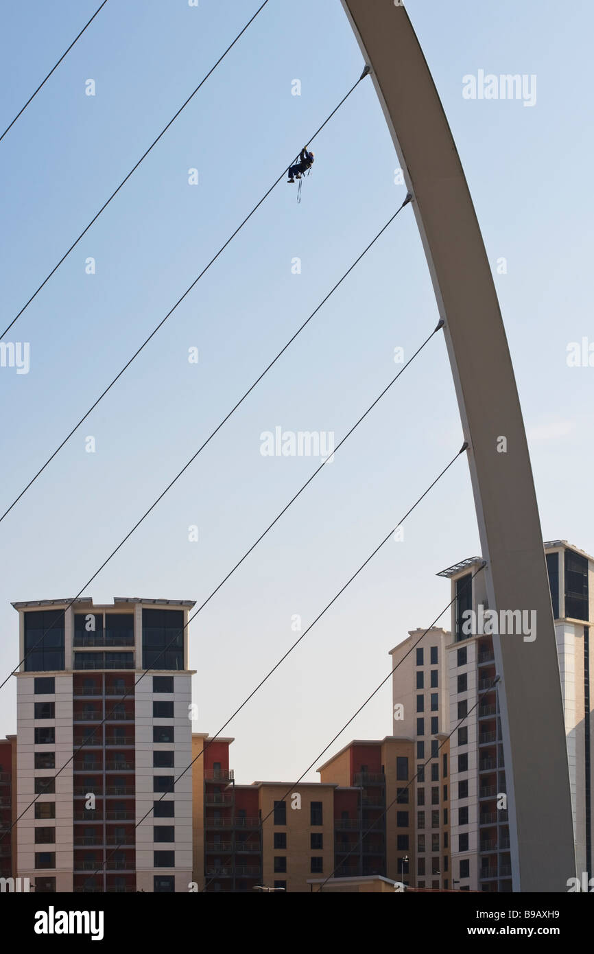 Steeplejack climbing up the metal cables of the Gateshead Millennium bridge to assess and repair the structure, Tyne and Wear Stock Photo