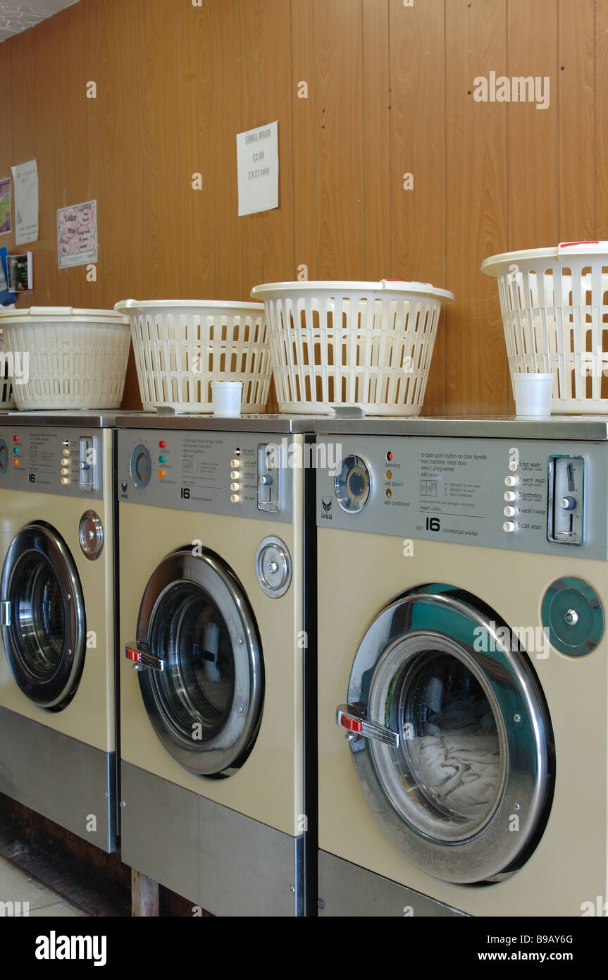 Plastic laundry baskets on top of washing machines in a wood paneled 70's  launderette Stock Photo - Alamy