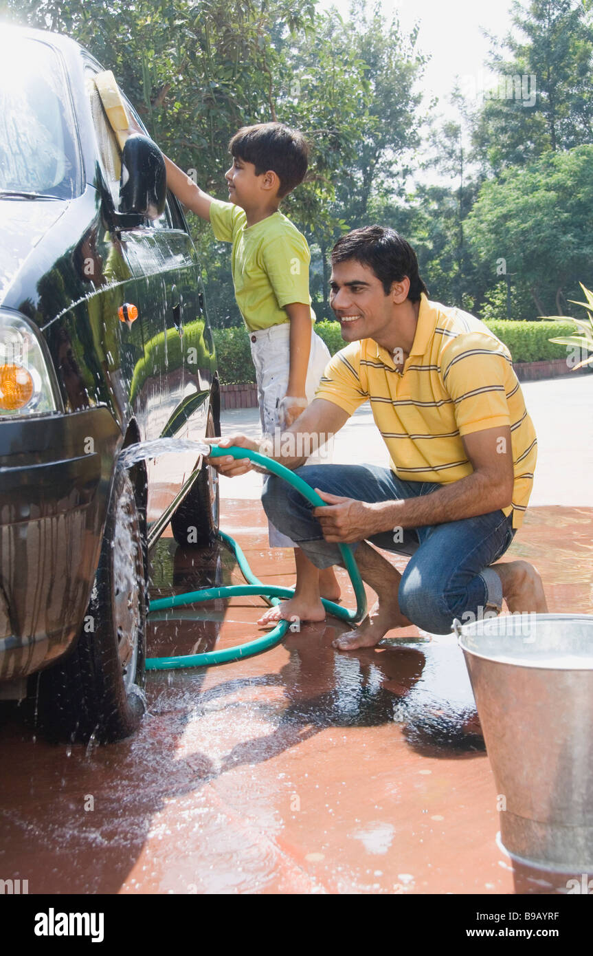 Boy helping his father washing a car and smiling Stock Photo Alamy