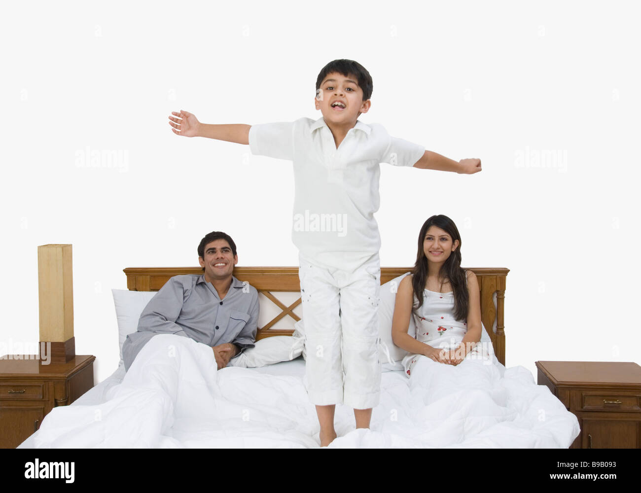 Couple looking at their son playing on the bed Stock Photo