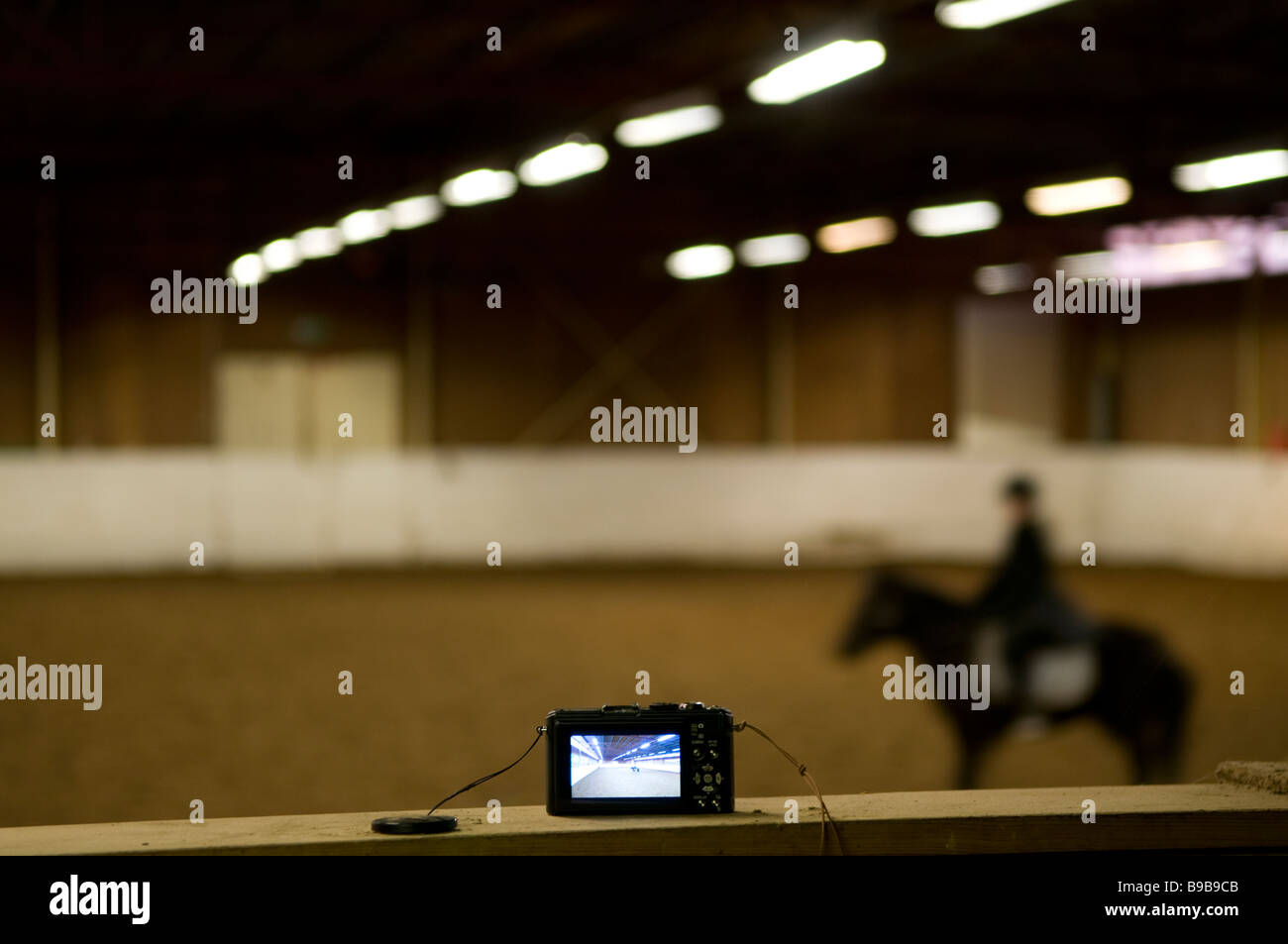 Girl riding a horse in a riding stable. A camera is filming her Stock