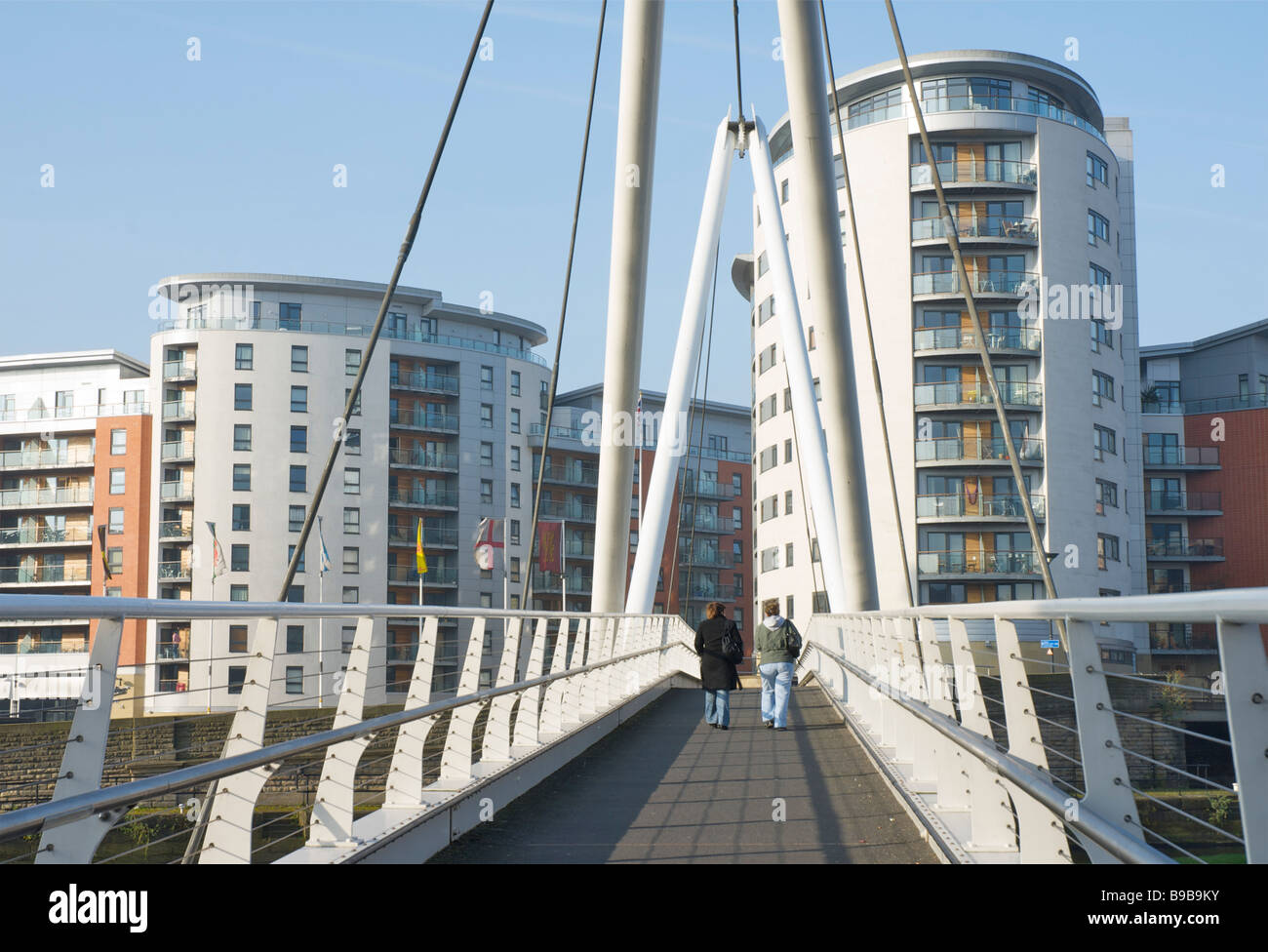 Two people walking across the River Aire on Knight's Way Bridge, Clarence Dock, Leeds, West Yorkshire, England, UK Stock Photo