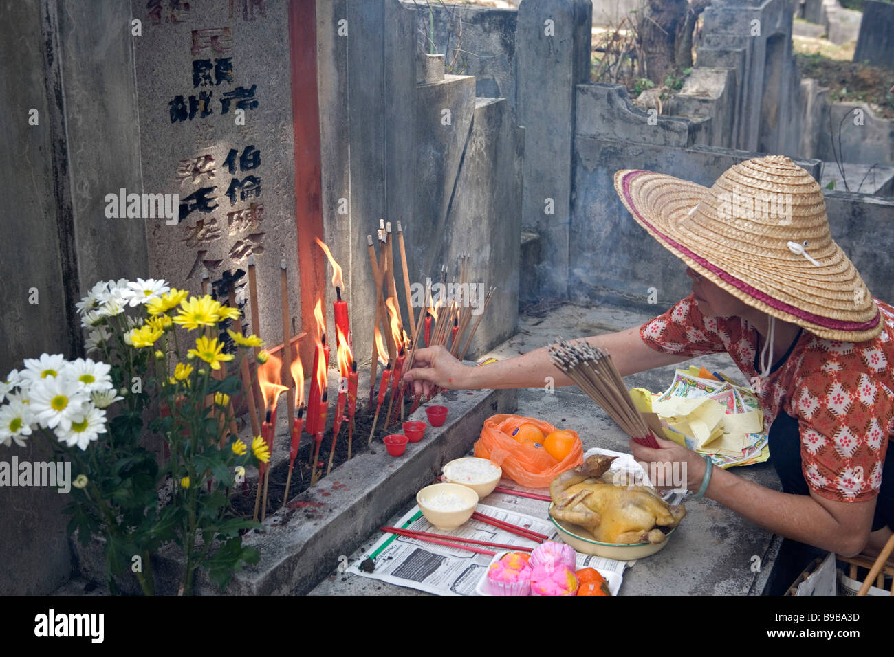 Offerings and lighting up of josticks at a tombstone during Qing Ming in Malaysia, South East Asia Stock Photo