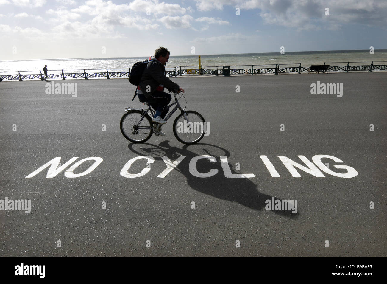 A cyclist ignoring a 'No Cycling sign on the seafront at Brighton and Hove. Stock Photo