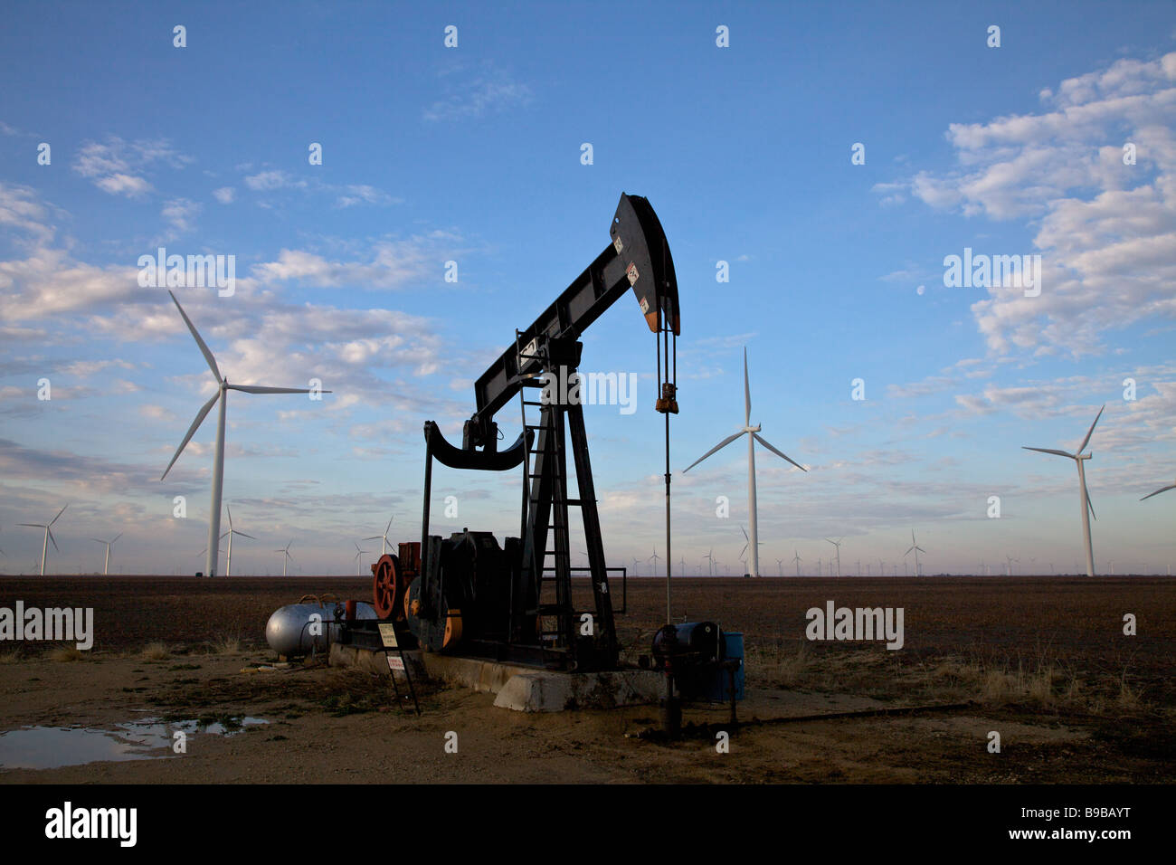 An oil well in the west Texas desert near wind turbines generating electrical power at Horse Hollow Wind Farm Nolan county Texas Stock Photo