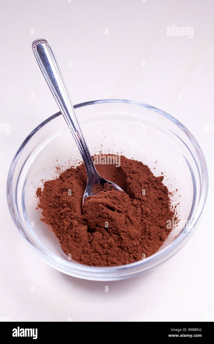 COCOA IN POWDER IN A GLASS BOWL WITH SPOON Stock Photo