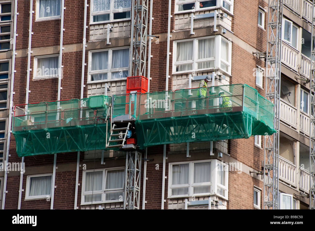 Two workmen on a high platform fixing facia panel rails on 'high rise' flats Stock Photo