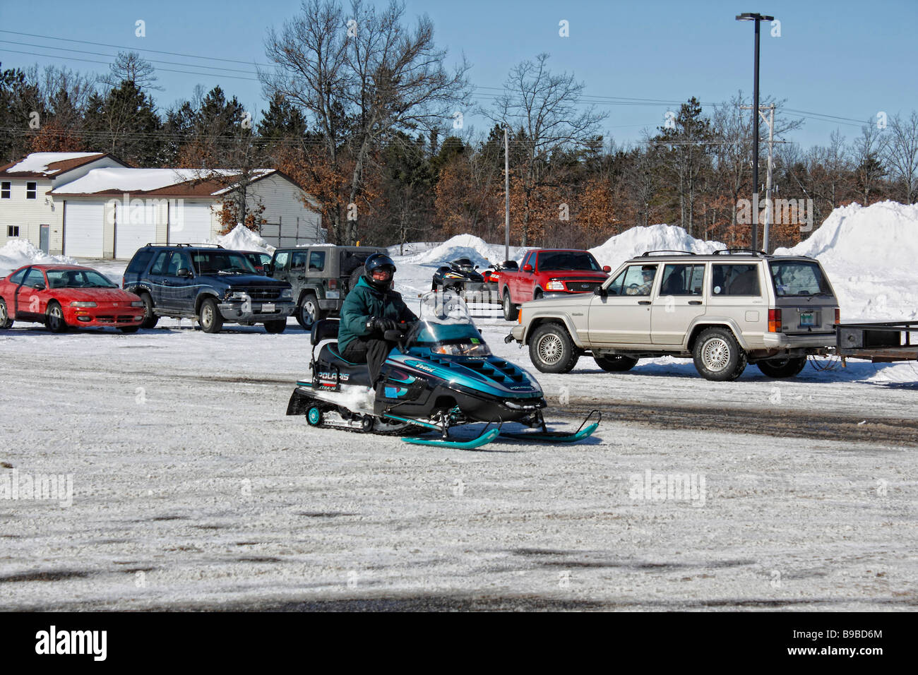 A young man rides a snowmobile in a small town in USA US lifestyle daily life a drifts of snow from above overhead  hi-res Stock Photo