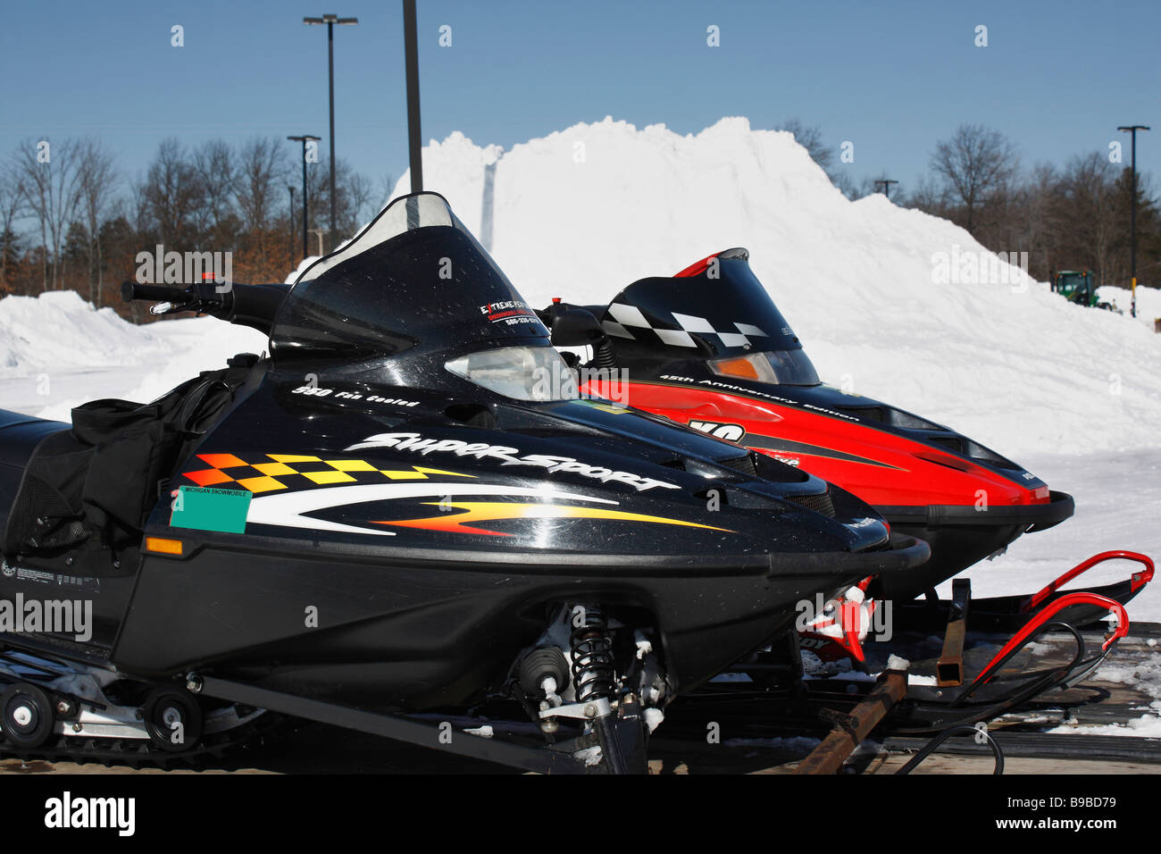 Snowmobile parked on the city street in the drifts of snow in a small town nobody none in MI USA US lifestyle of snow hi-res Stock Photo