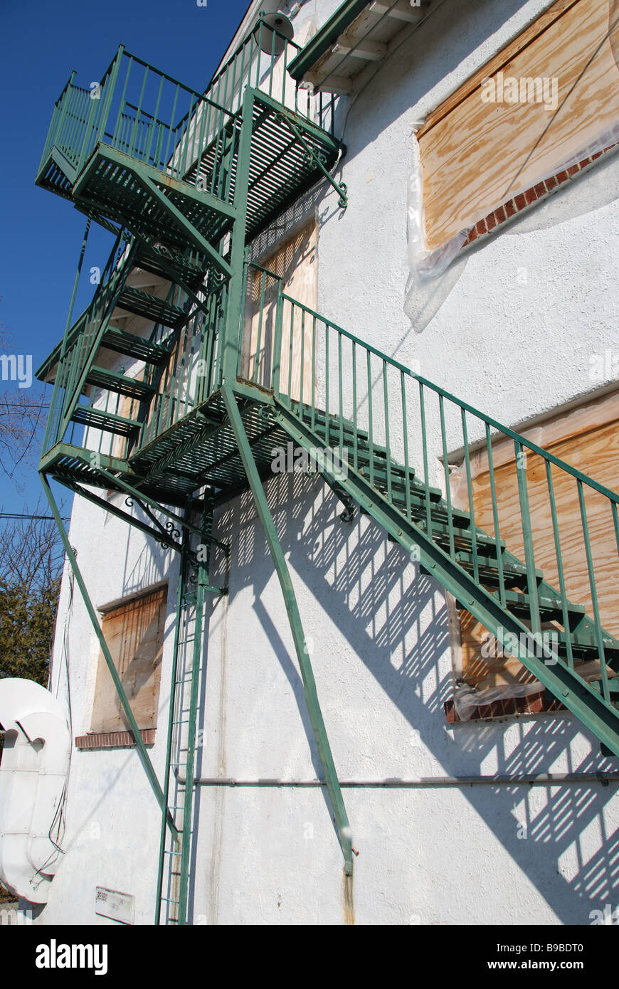 A green fire escape on the side of a boarded up and abandoned former luxury hotel building in Toronto Canada. Stock Photo