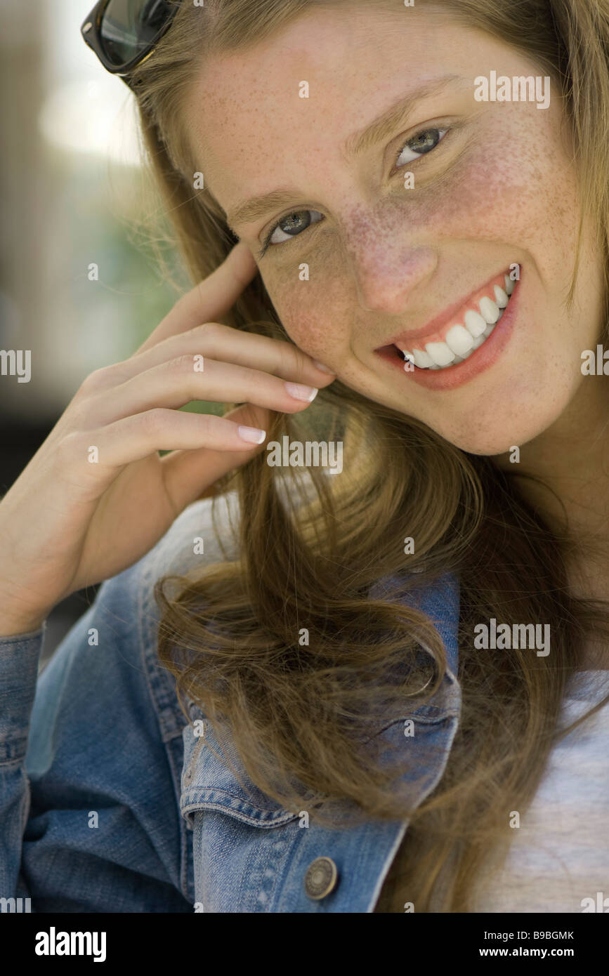 Young woman with freckles smiling at camera, portrait Stock Photo