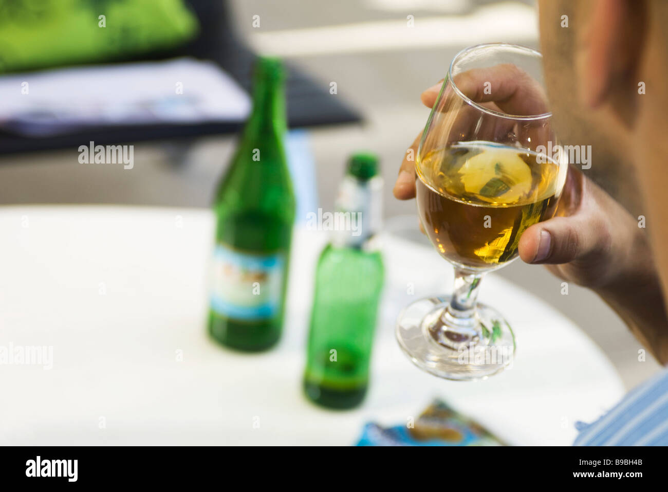 Man drinking beer from a glass, cropped, over the shoulder view Stock