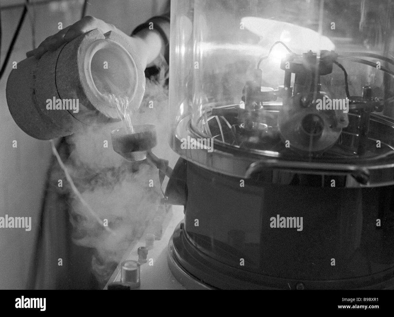Researcher pouring liquid nitrogen into an installation for examining live organisms cells