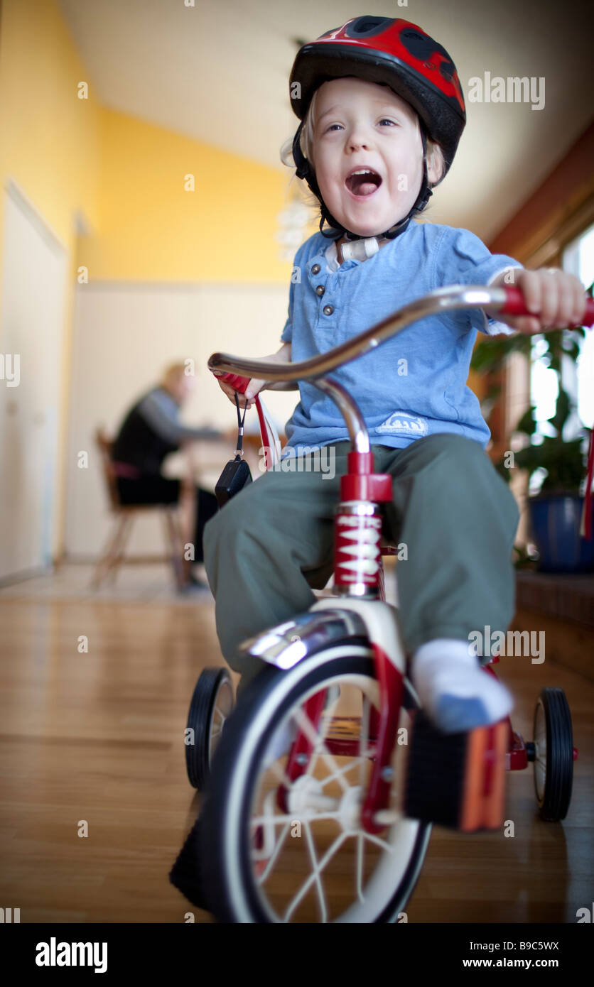 Toddler riding a tricycle around the house Stock Photo