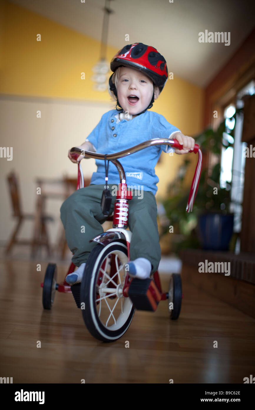 Toddler riding a tricycle around the house Stock Photo Alamy