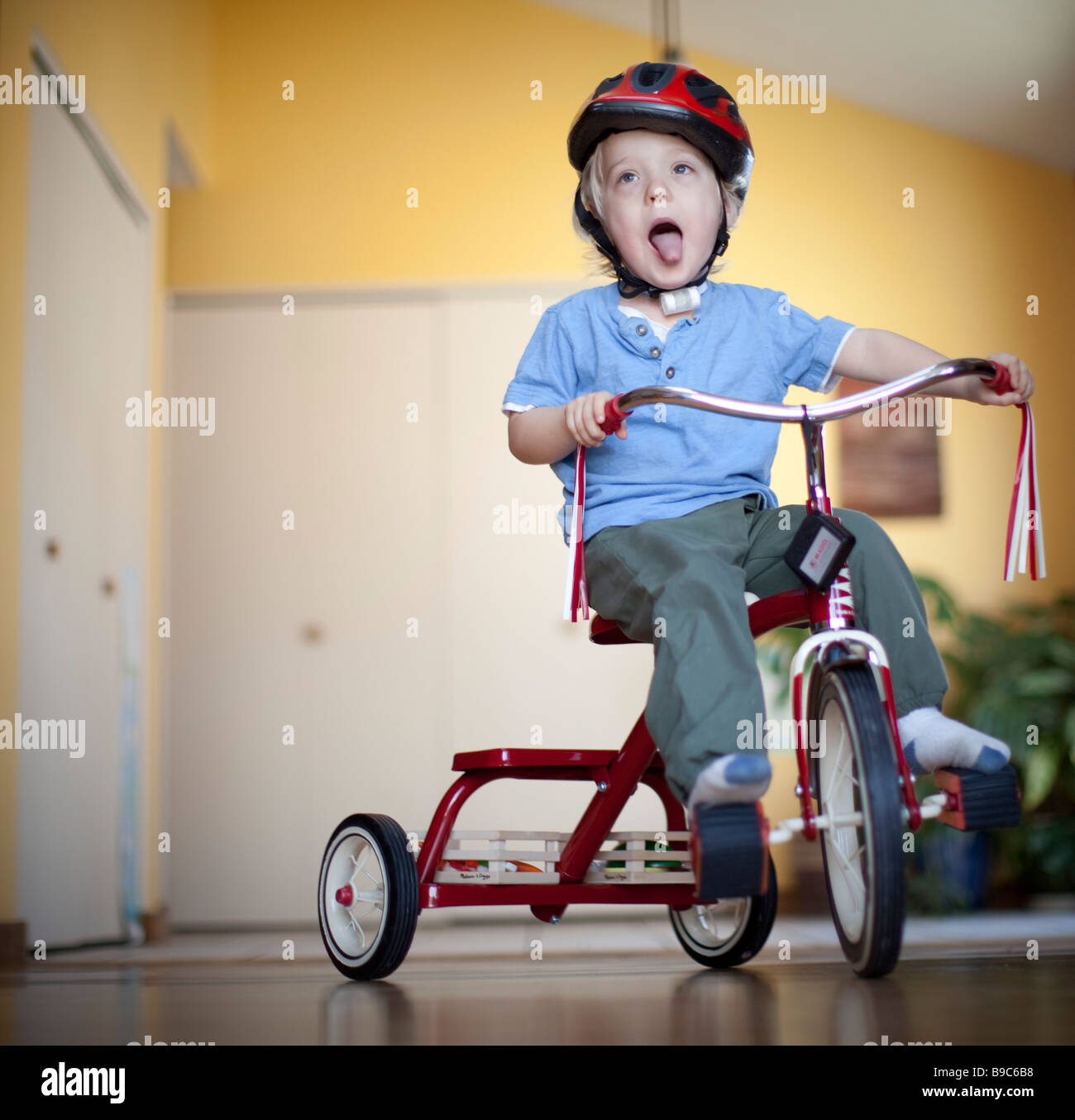 Toddler riding a tricycle around the house Stock Photo Alamy