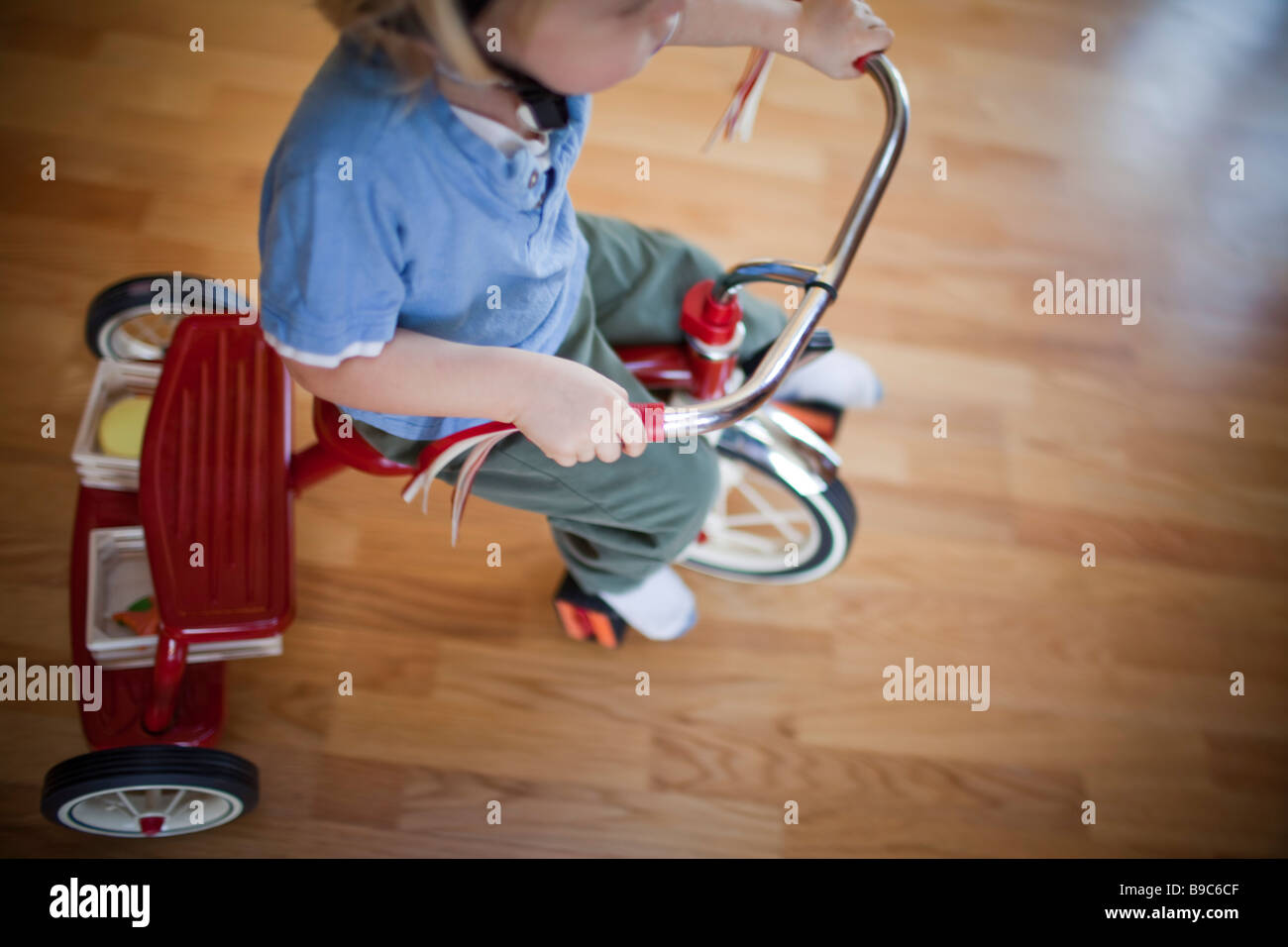 Toddler riding a tricycle around the house Stock Photo Alamy