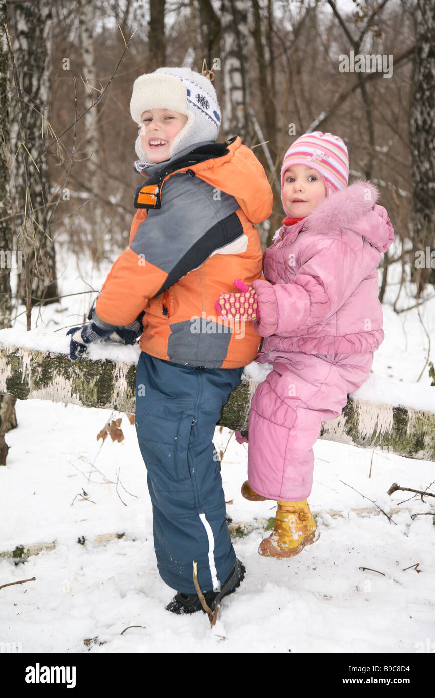 boy and girl sit on fallen tree in forest in winter Stock Photo - Alamy