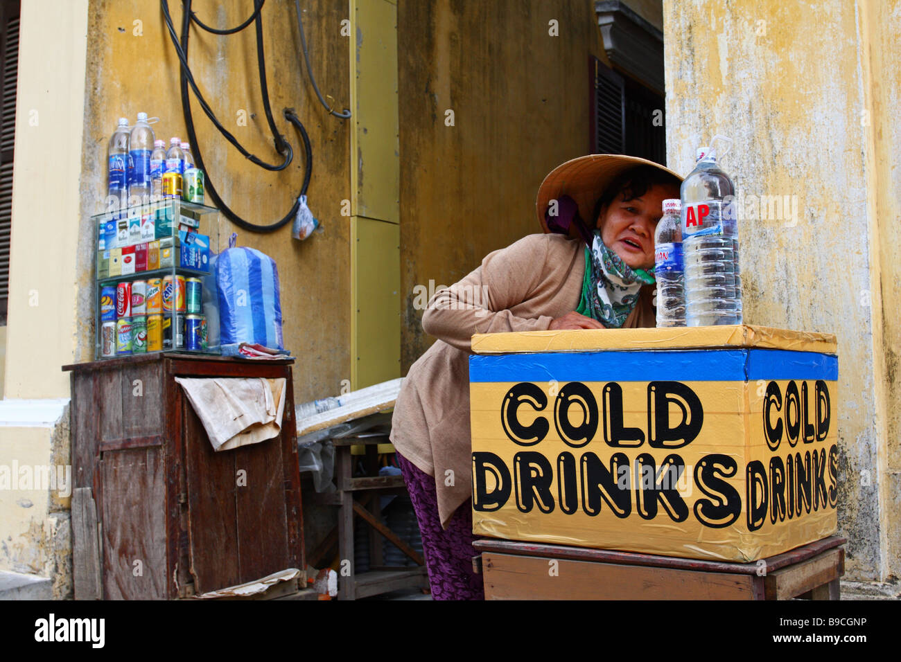 Street Scene. Woman with a traditional conical hat selling cold drinks